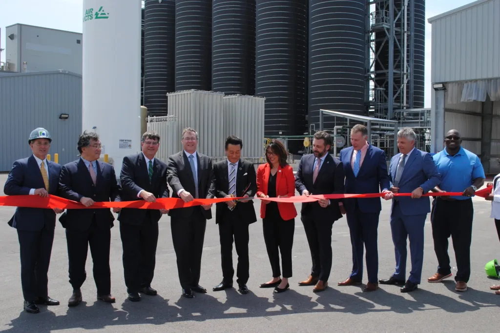 Officials at a ribbon cutting holding a bow in front of Air Ducts