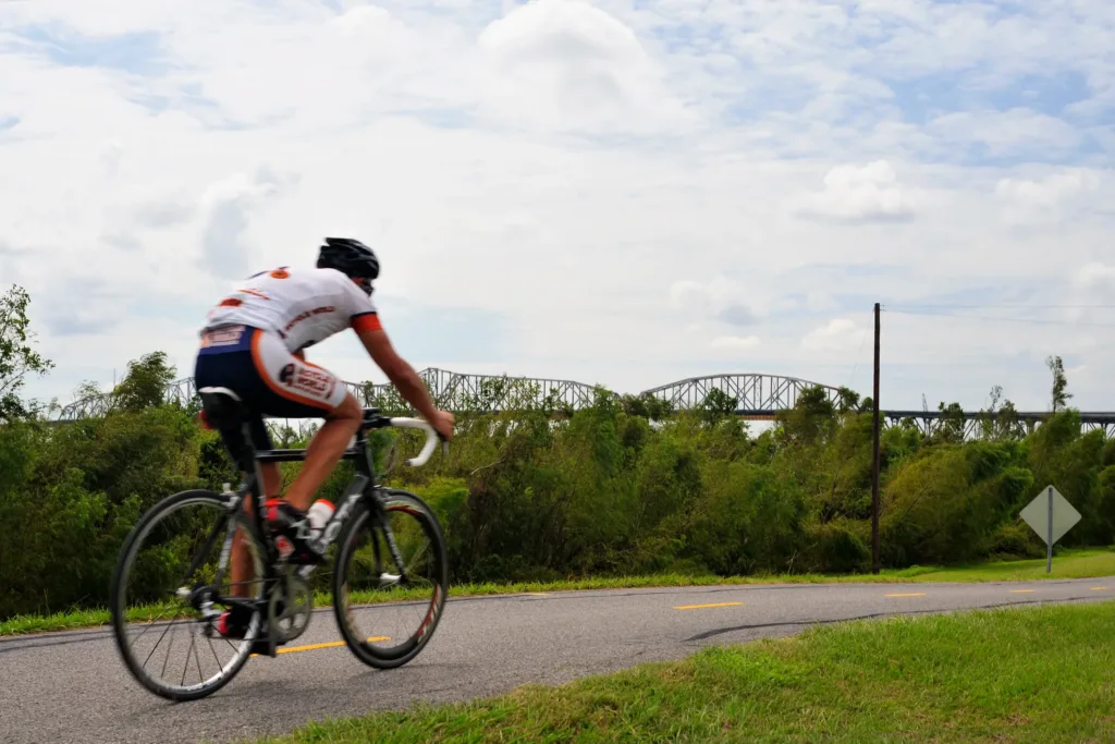 A man on a bike with the Huey P. bridge in the background