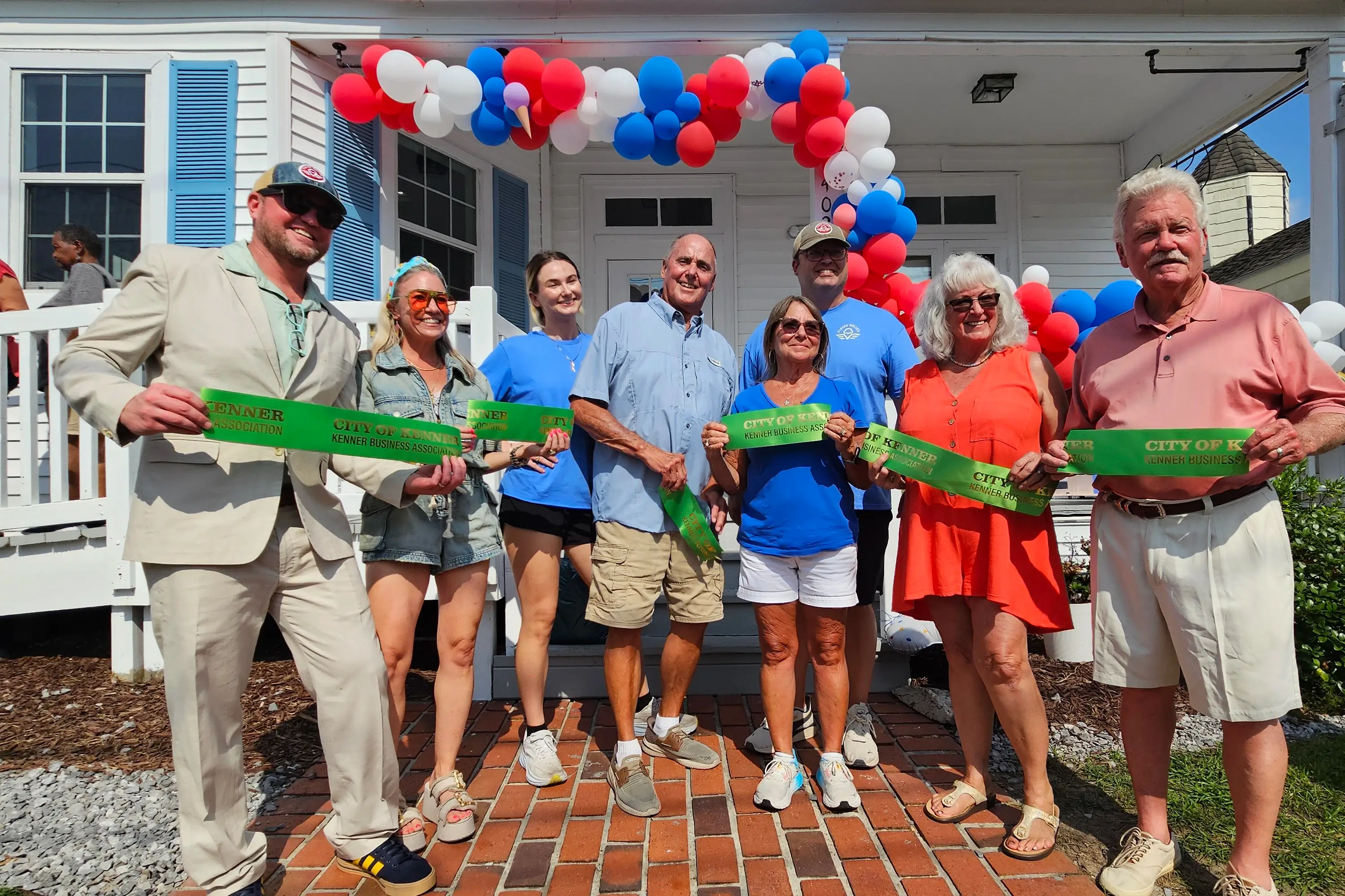 A family holding the City of Kenner Business Association ribbon