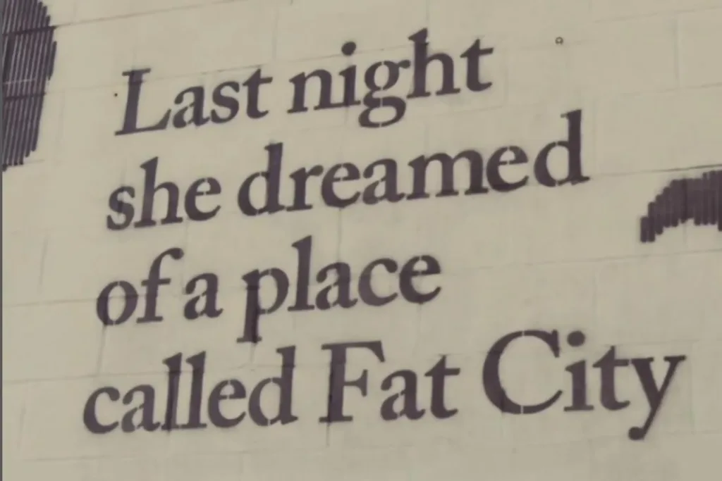 A mural stating "Last night she dreamed of a place called Fat City"