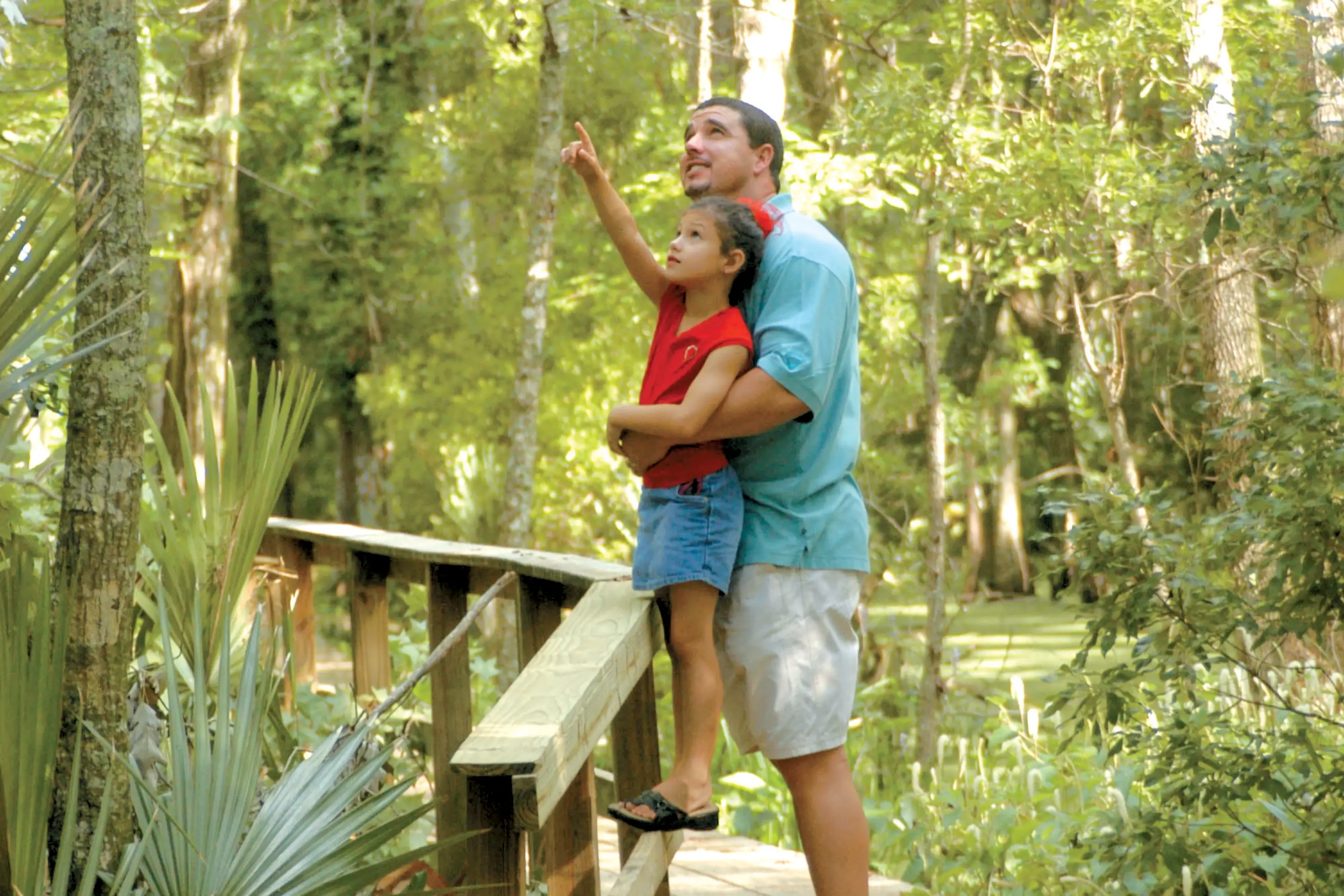 A father holding his daughter up in Jean Lafitte Park