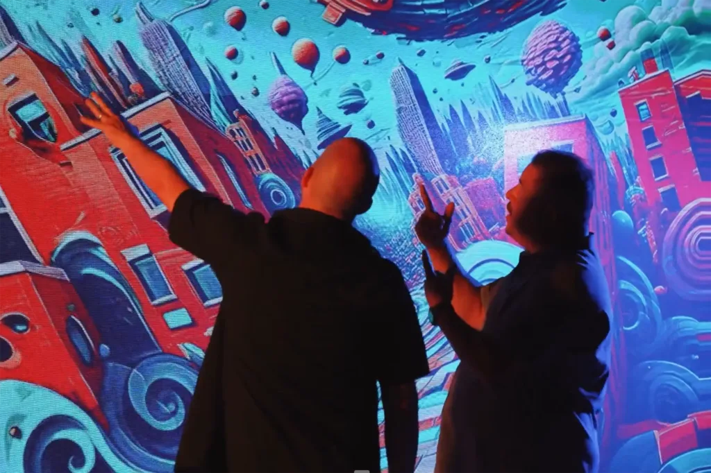 Two people looking and pointing at an illustration on a large screen