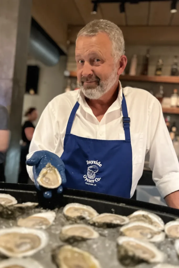A man in a Bayside Oyster Co. apron holding grand isle jewels