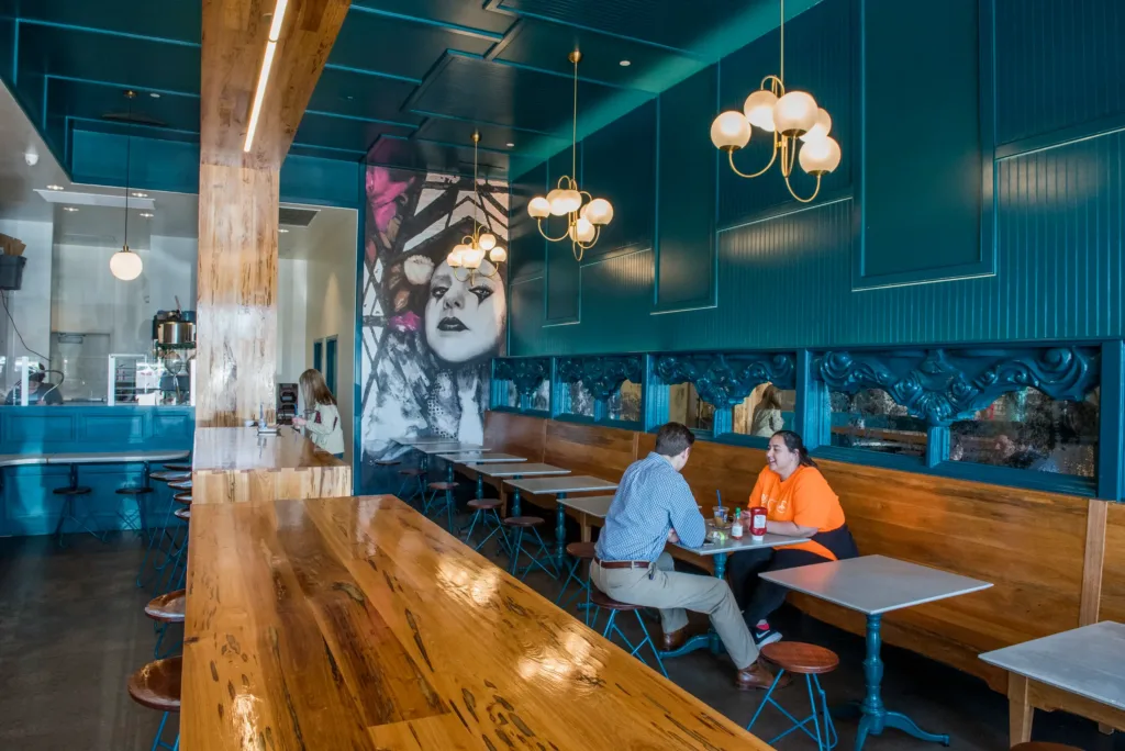 People sitting at District Donuts with a view of the mural in the background