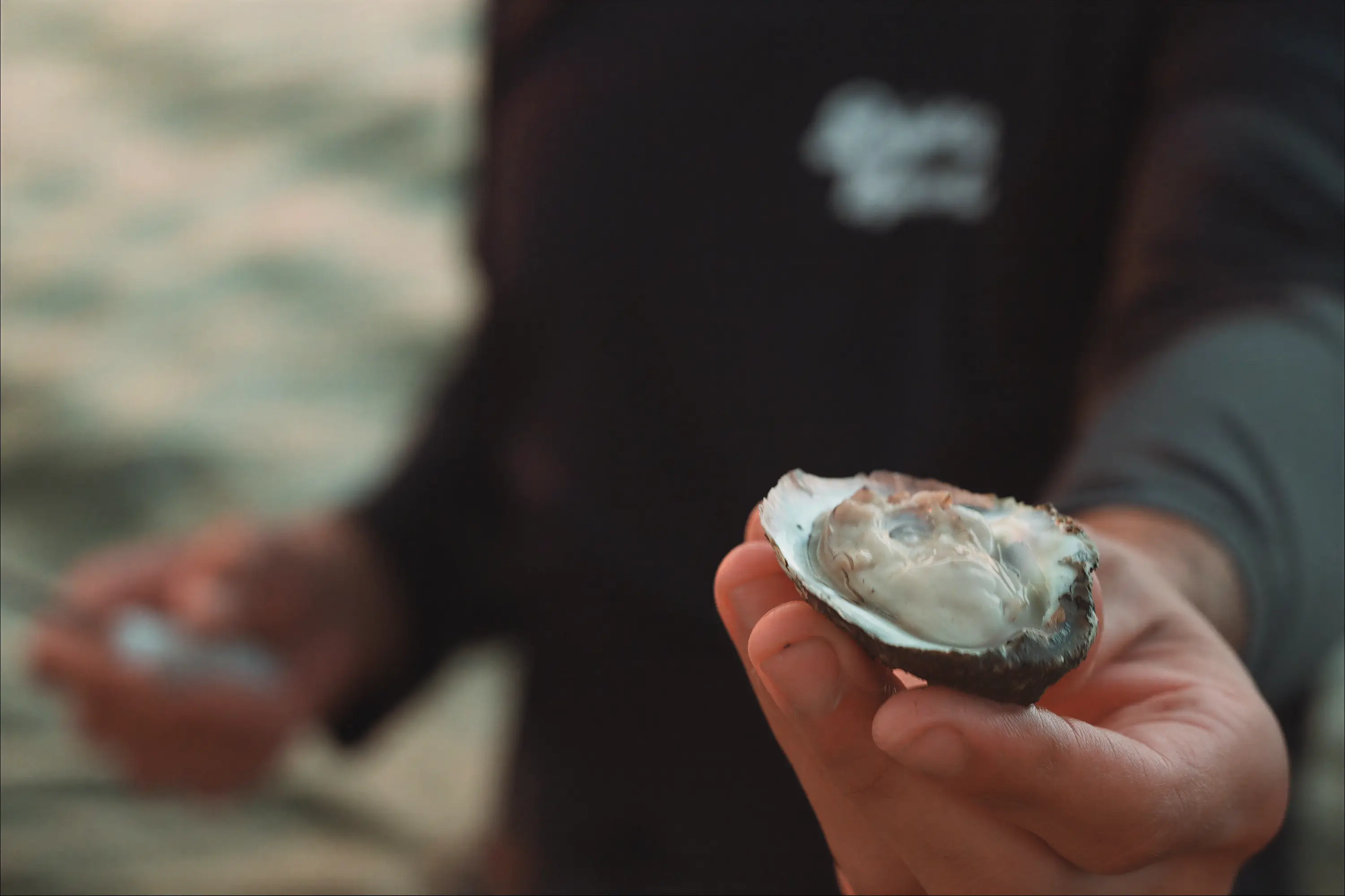 A man holding an oyster on the half shell