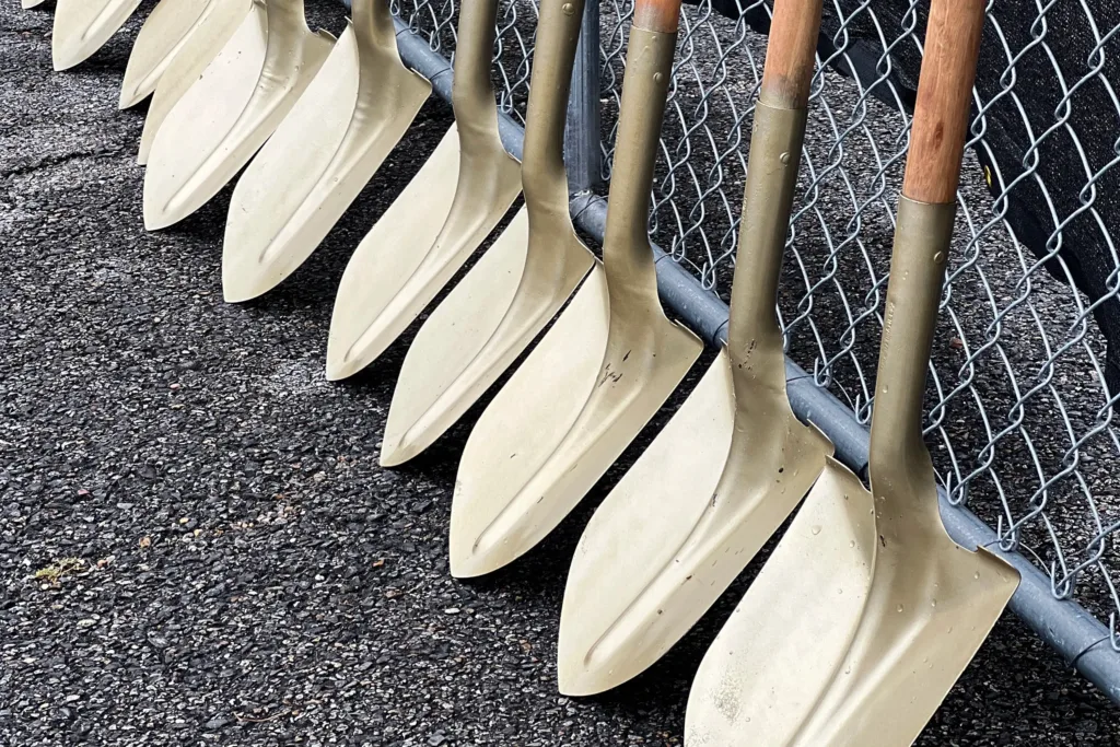 Shovels leaning against a chain-link fence